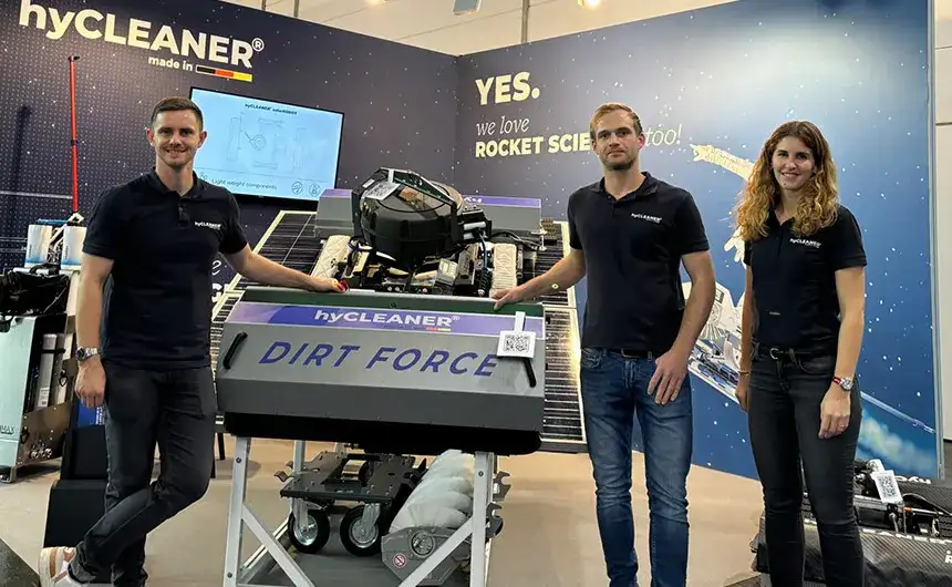 Drei hyCleaner Mitarbeiter stehen auf einer Messe an einem DIRT FORCE