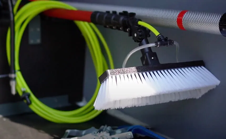 Eine Handbürste mit aufgerolltem Schlauch in einer Halterung